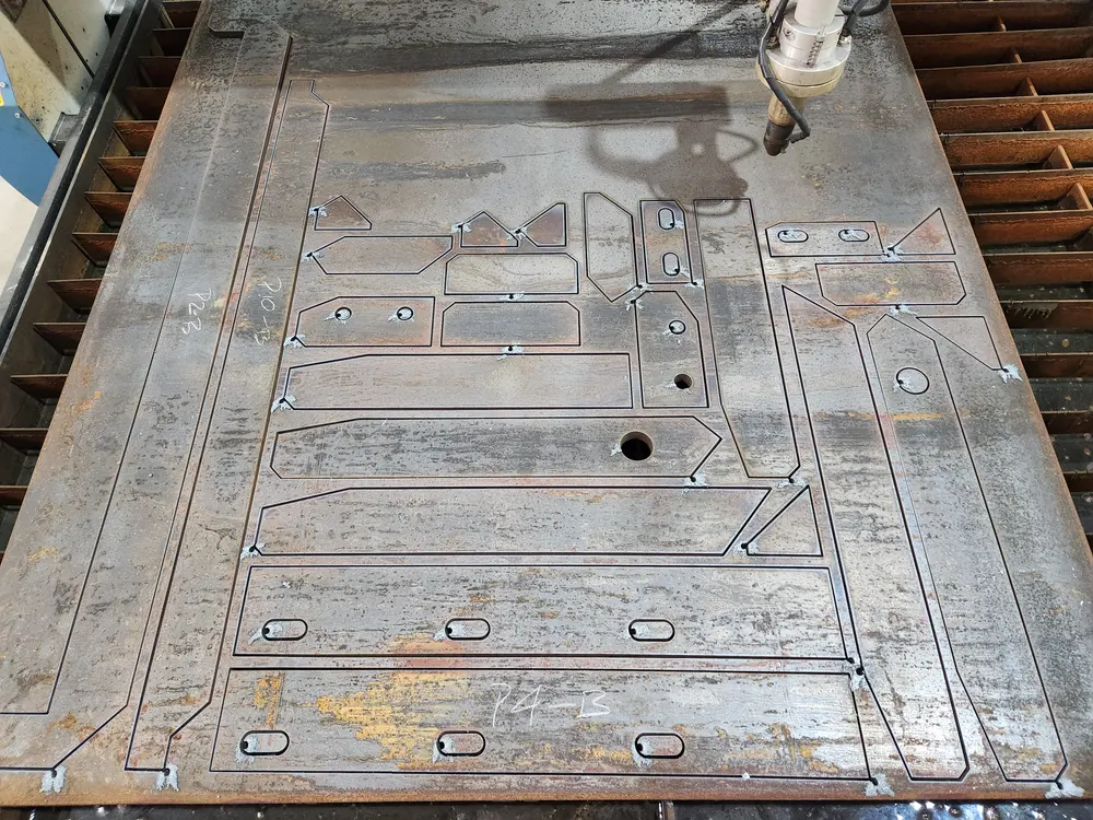 CNC plasma cutting table with steel plate parts cut from a single sheet at Q² Machines