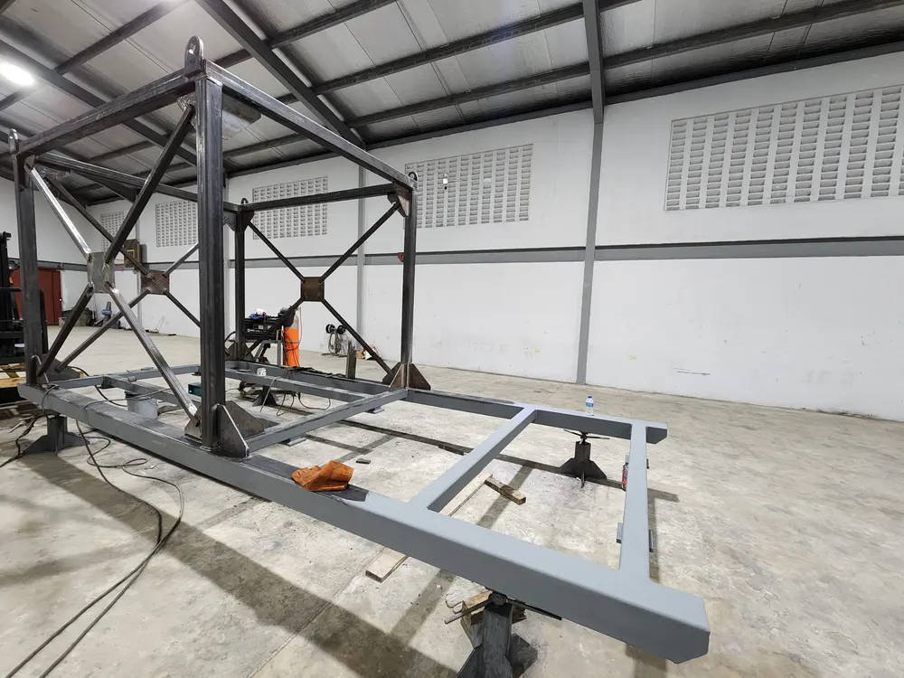 Welded steel frame with lifting lugs standing on a painted steel base frame in the Q² Machines workshop