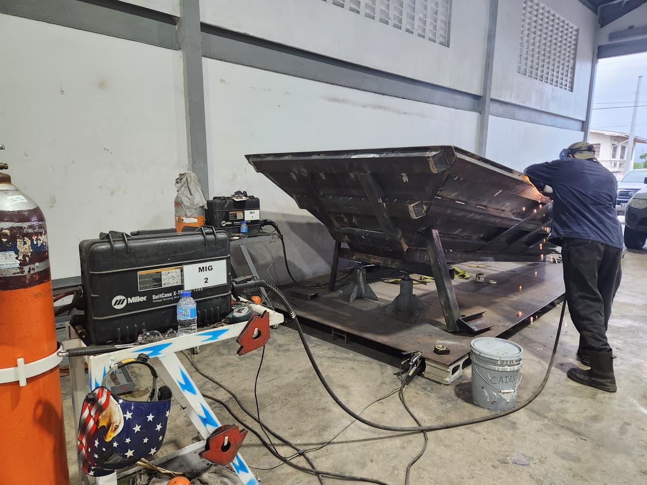 Technician welding a heavy steel plate fabrication in a workshop